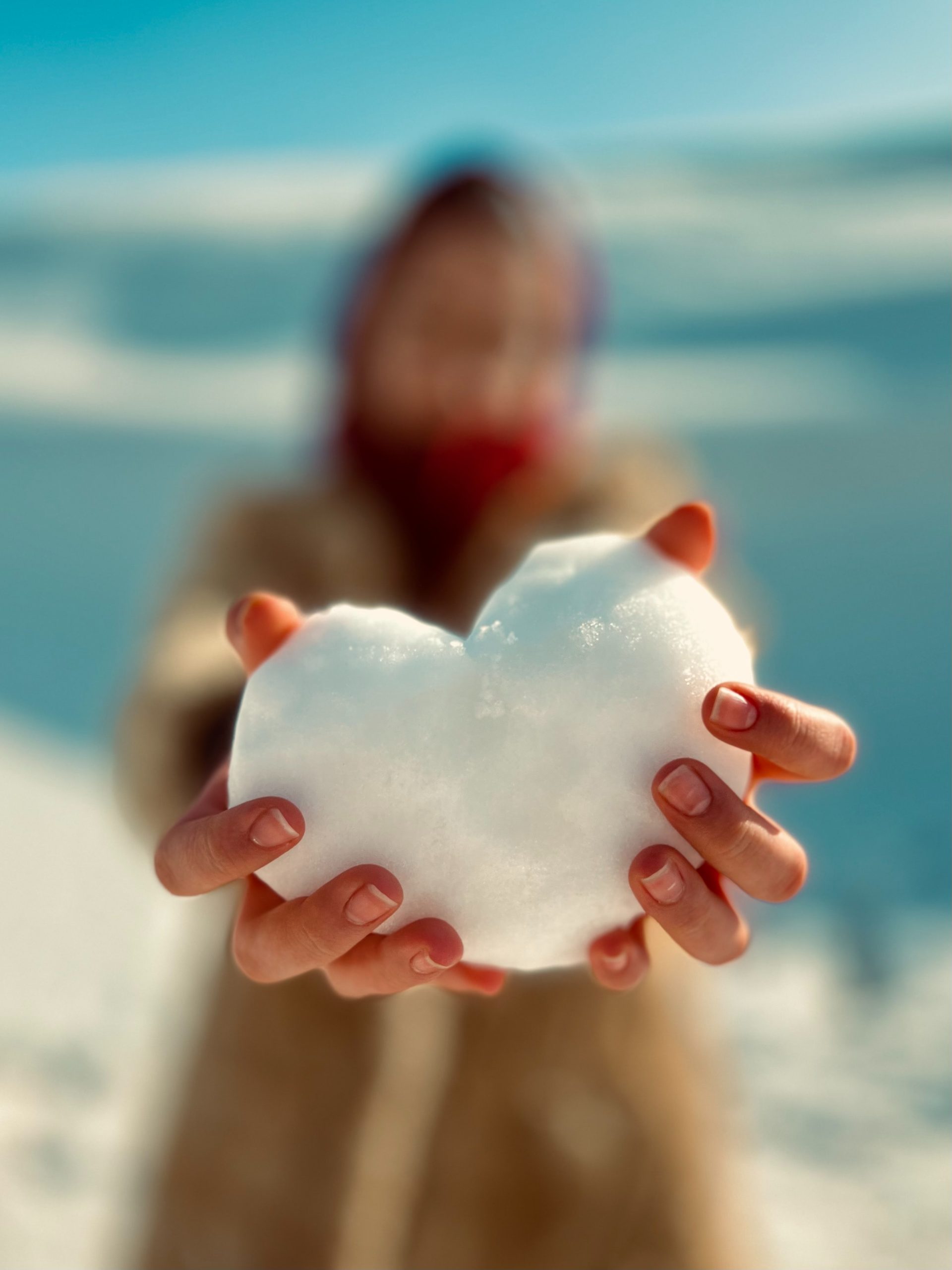 two hands holding a heart made of snow
