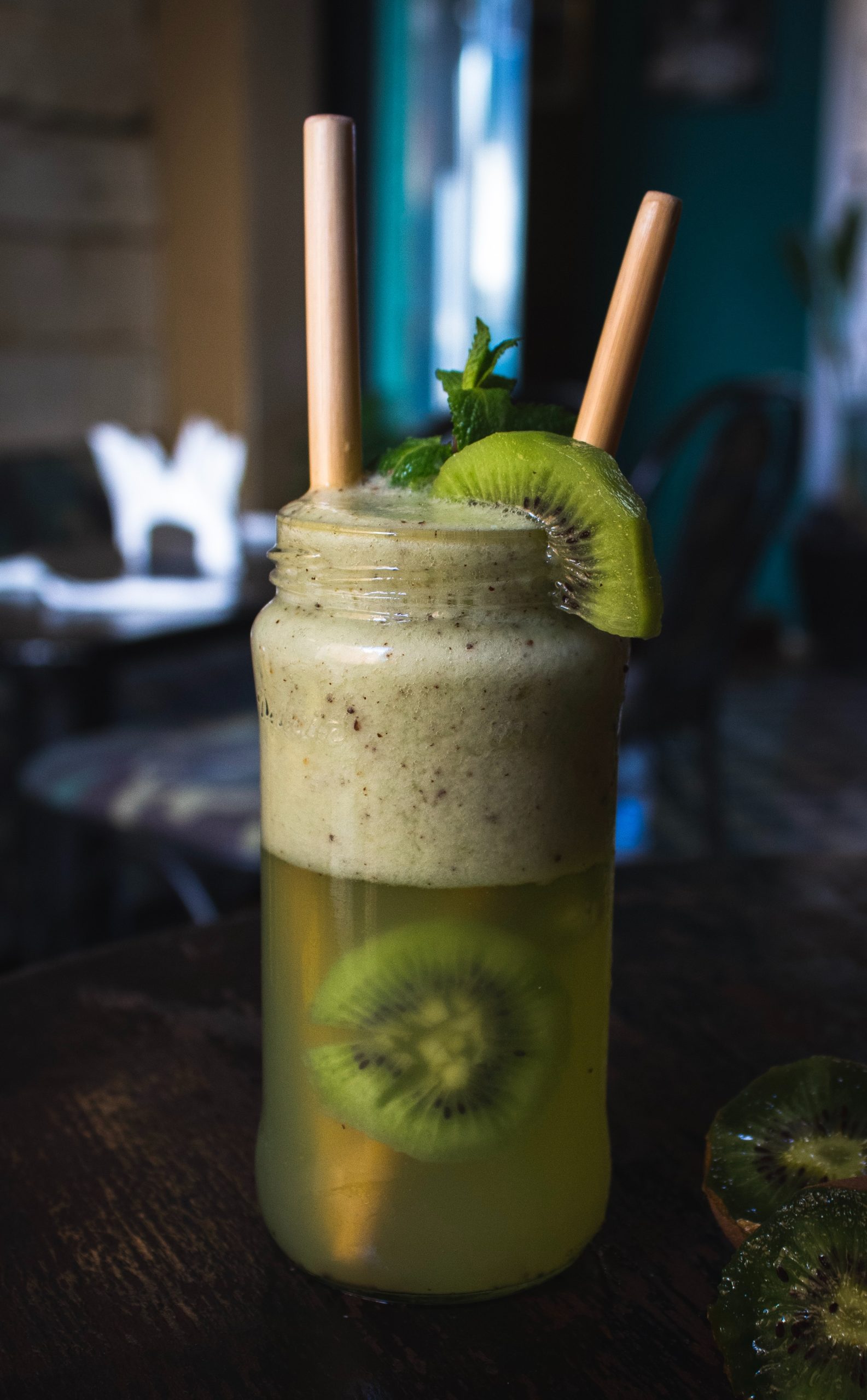 a mason jar filled with dense green juice and a slice of kiwi on the side of the jar
