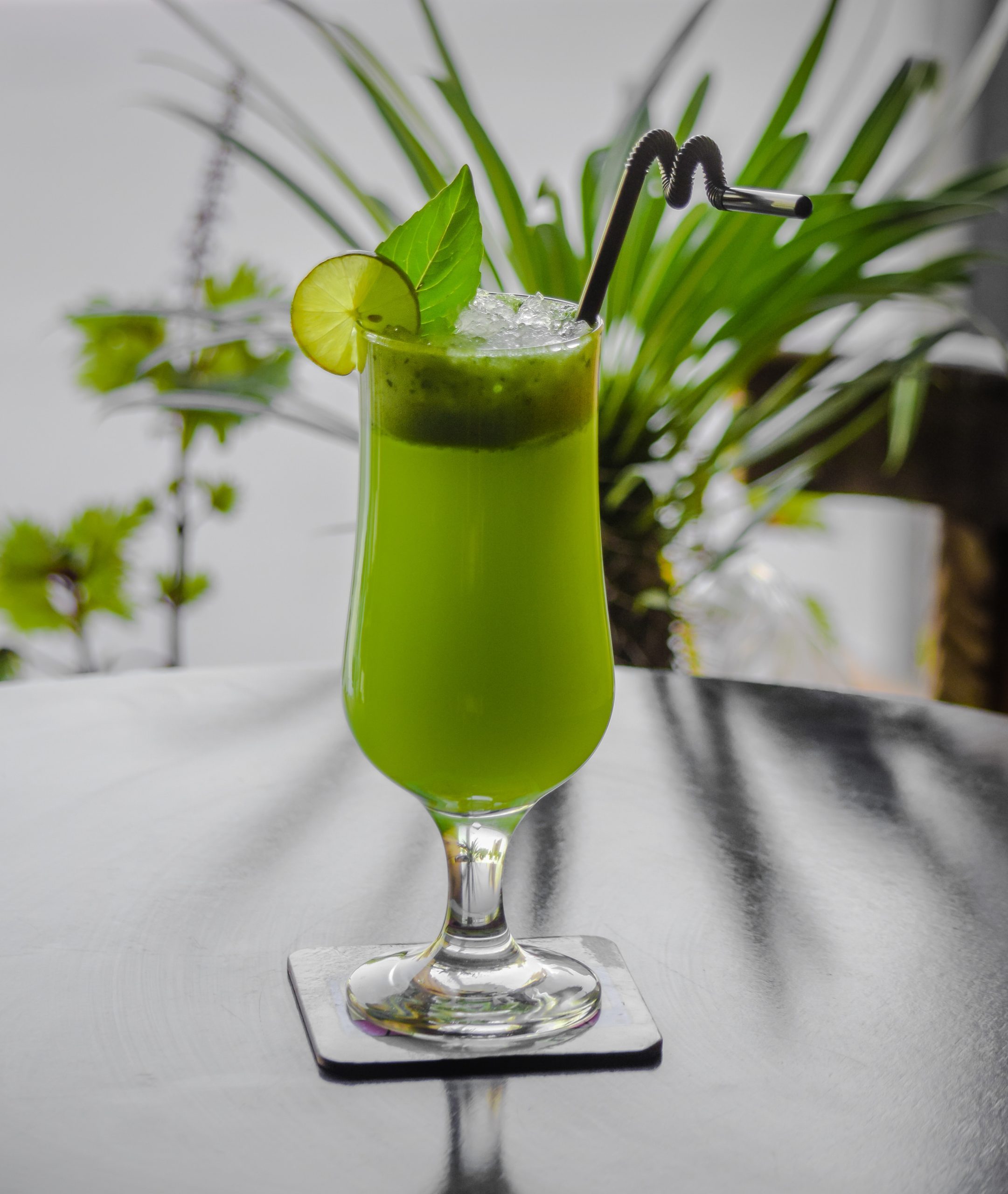 a tall glass with green juice on a sun drenched table